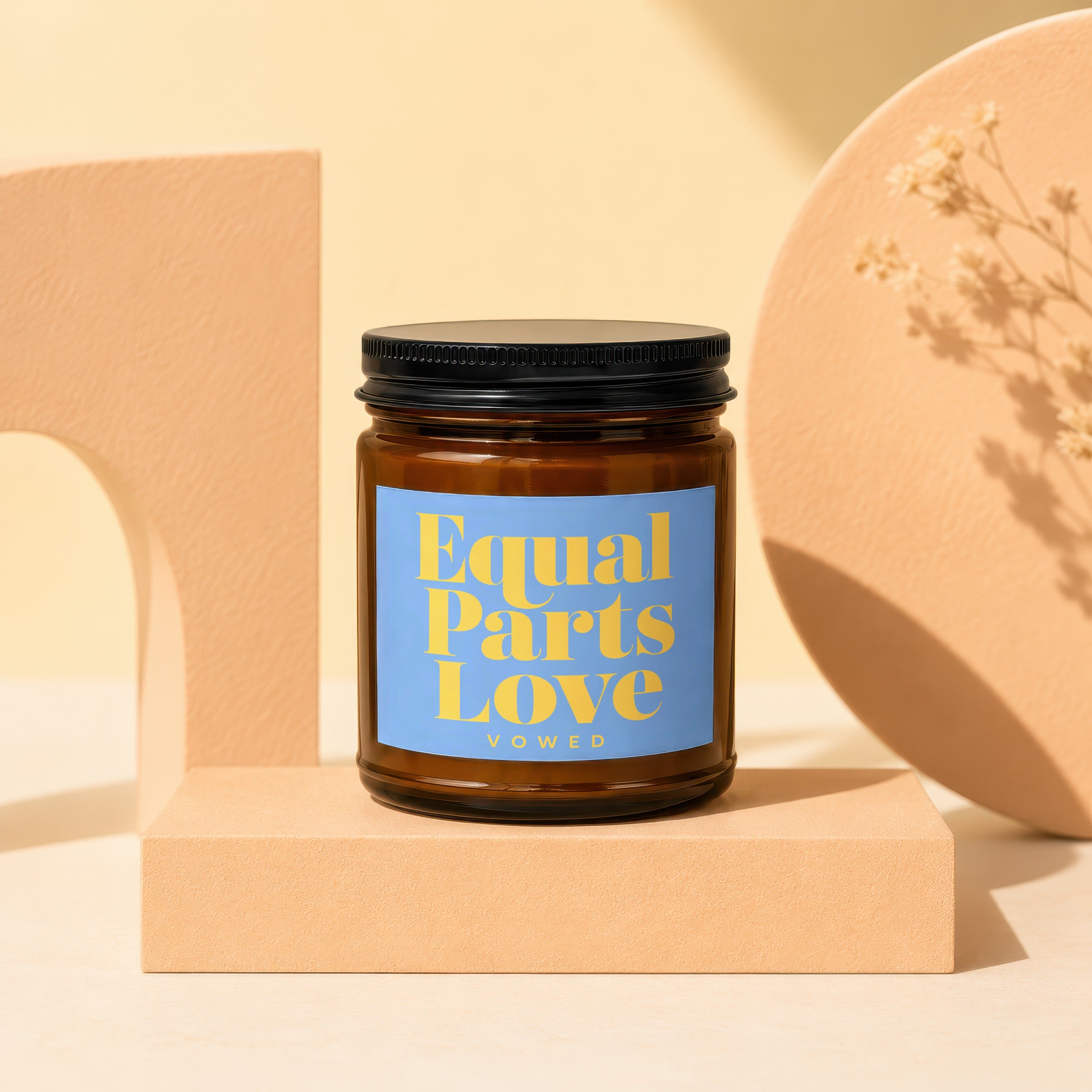 Amber glass candle with light blue label reading "Equal Parts Love VOWED."
