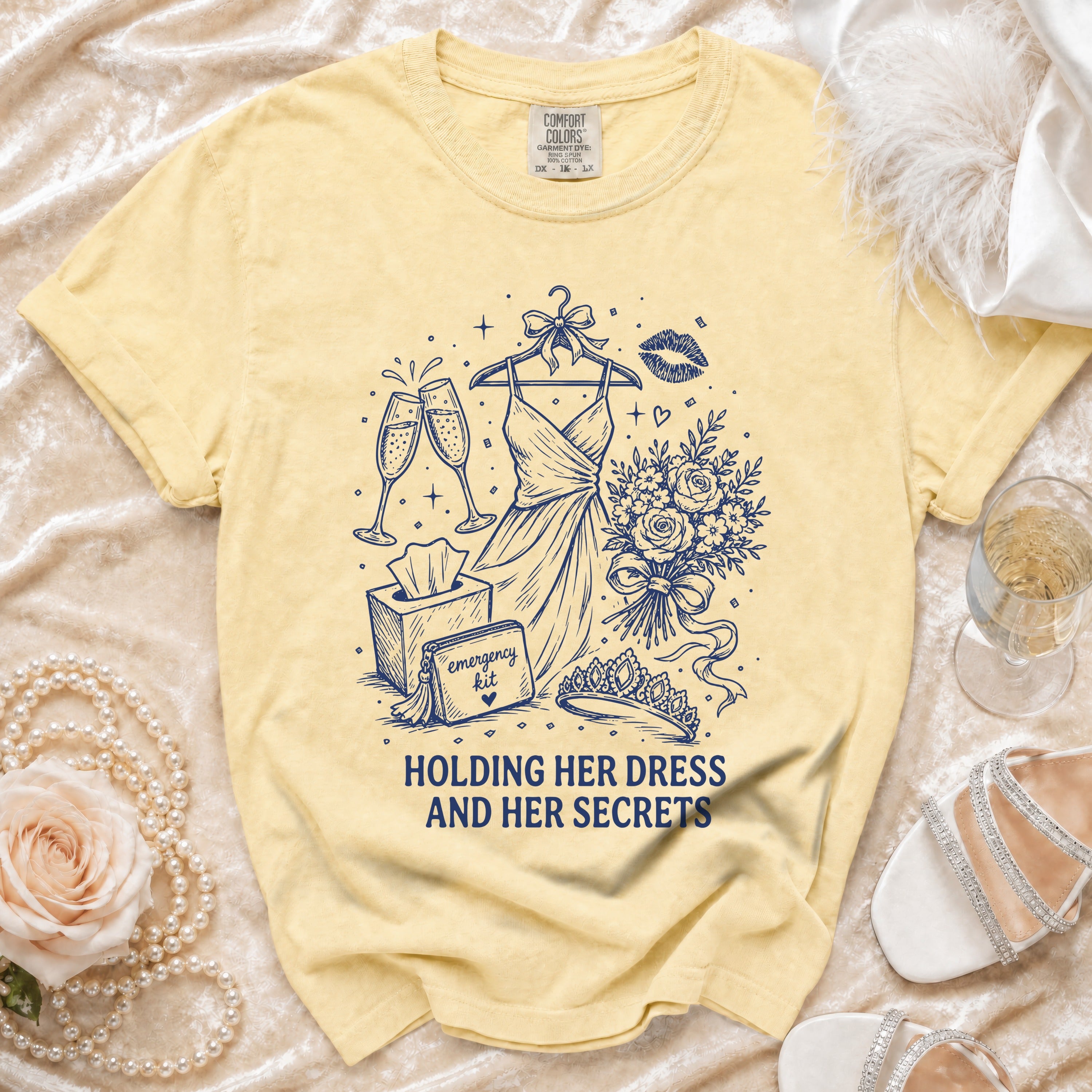 Yellow t-shirt with a navy graphic of a dress, champagne, roses, and the text "Holding Her Dress And Her Secrets".