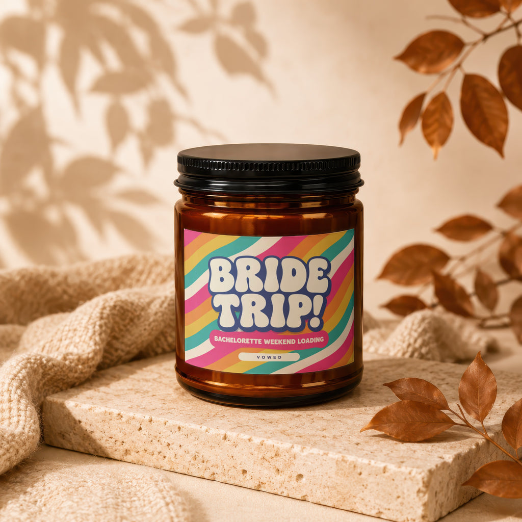 Amber jar candle with "BRIDE TRIP!" and "VOWED" text on a colorful label.