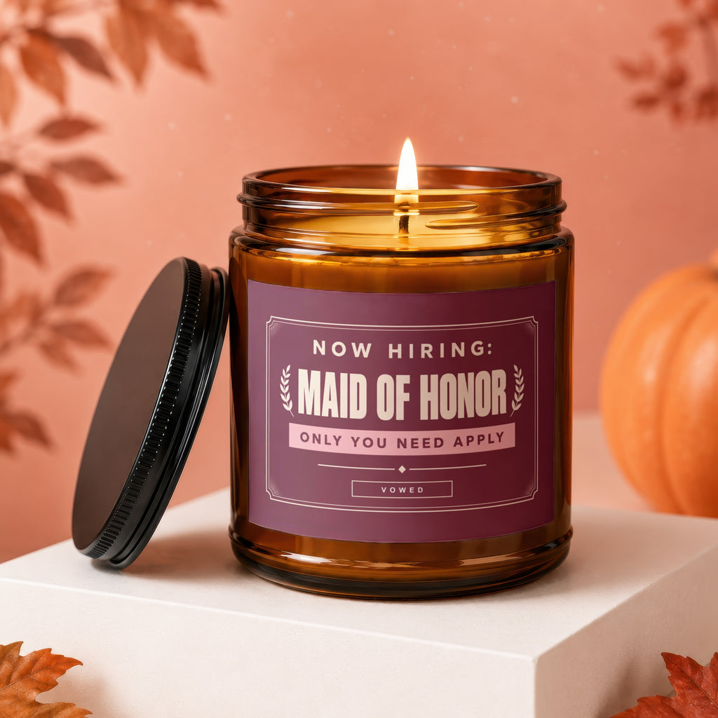 Lit candle in amber jar with "Now Hiring: Maid of Honor" label.