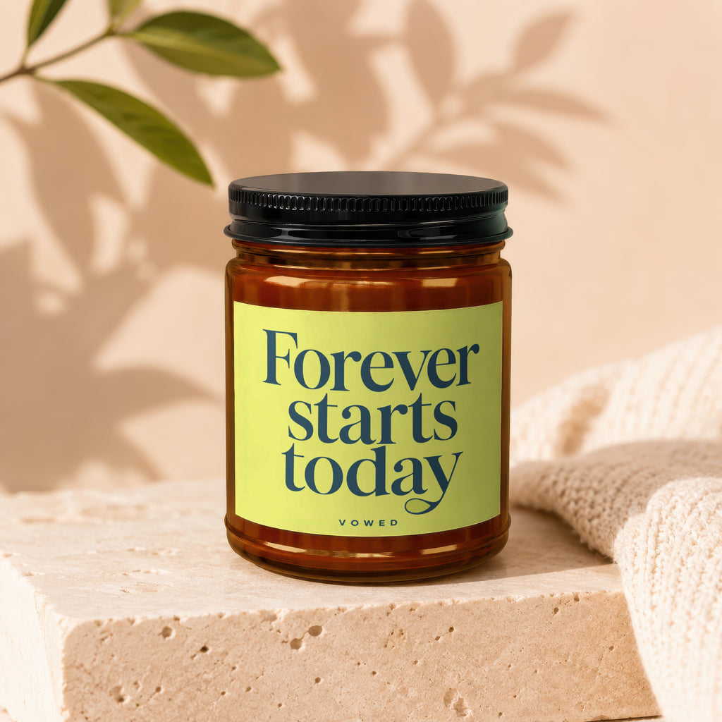 Amber jar candle with black lid and yellow label reading "Forever starts today" and "vowed".