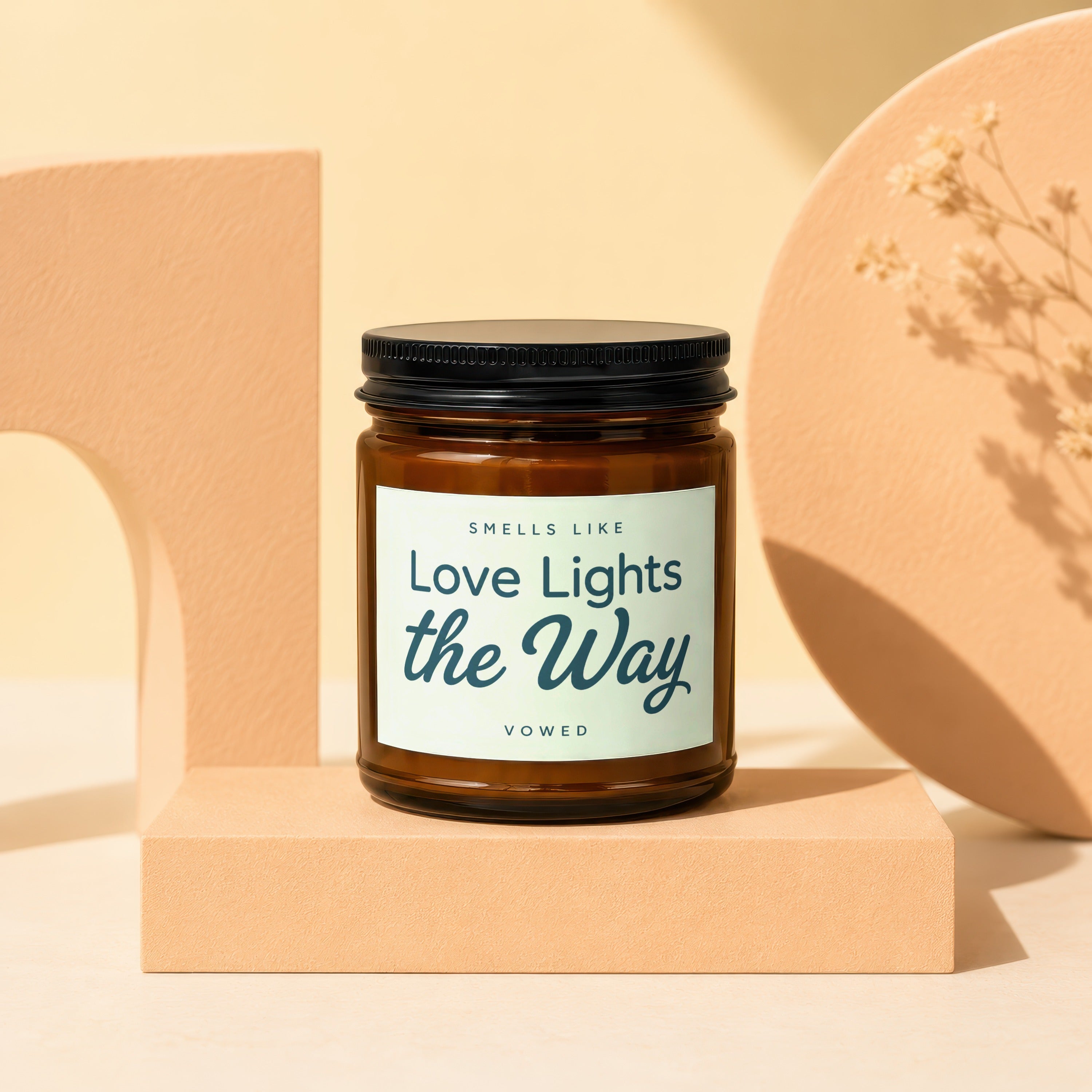 Amber candle with black lid reading "Smells Like Love Lights the Way Vowed".