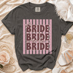 Dark grey t-shirt with "Bride to be Bride" text on striped pink background.