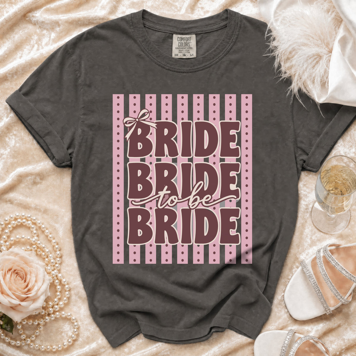 Dark grey t-shirt with "Bride to be Bride" text on striped pink background.