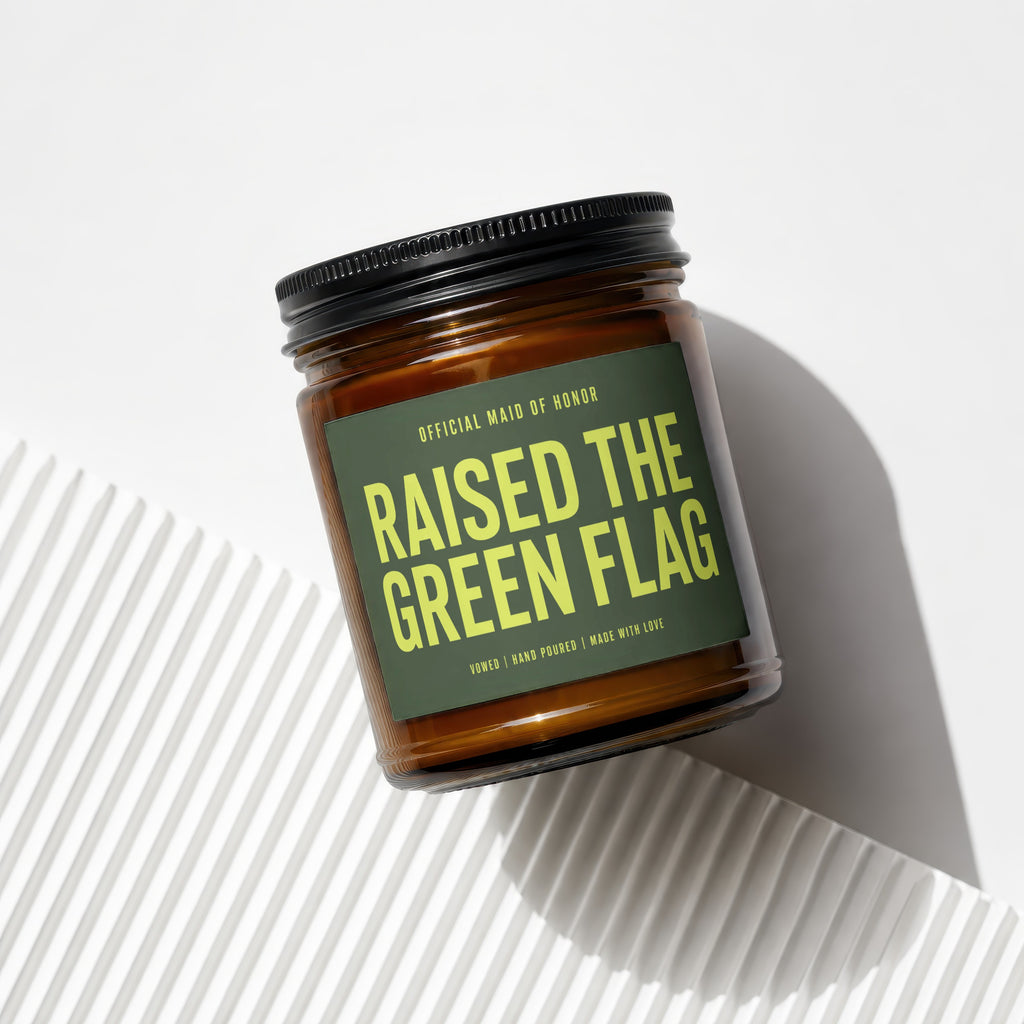 Amber jar candle with green label: "Raised the Green Flag".
