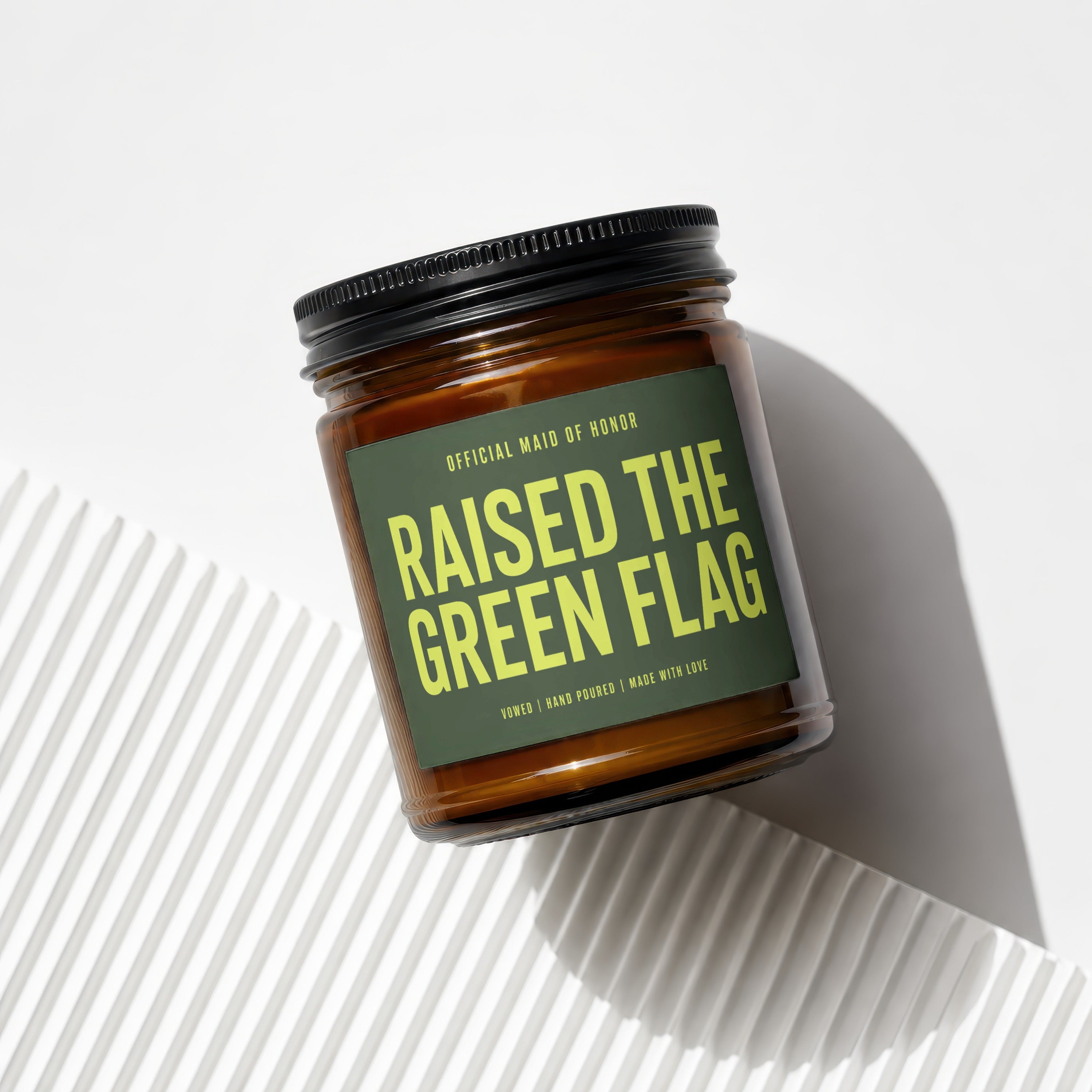 Amber jar candle with green label: "Raised the Green Flag".
