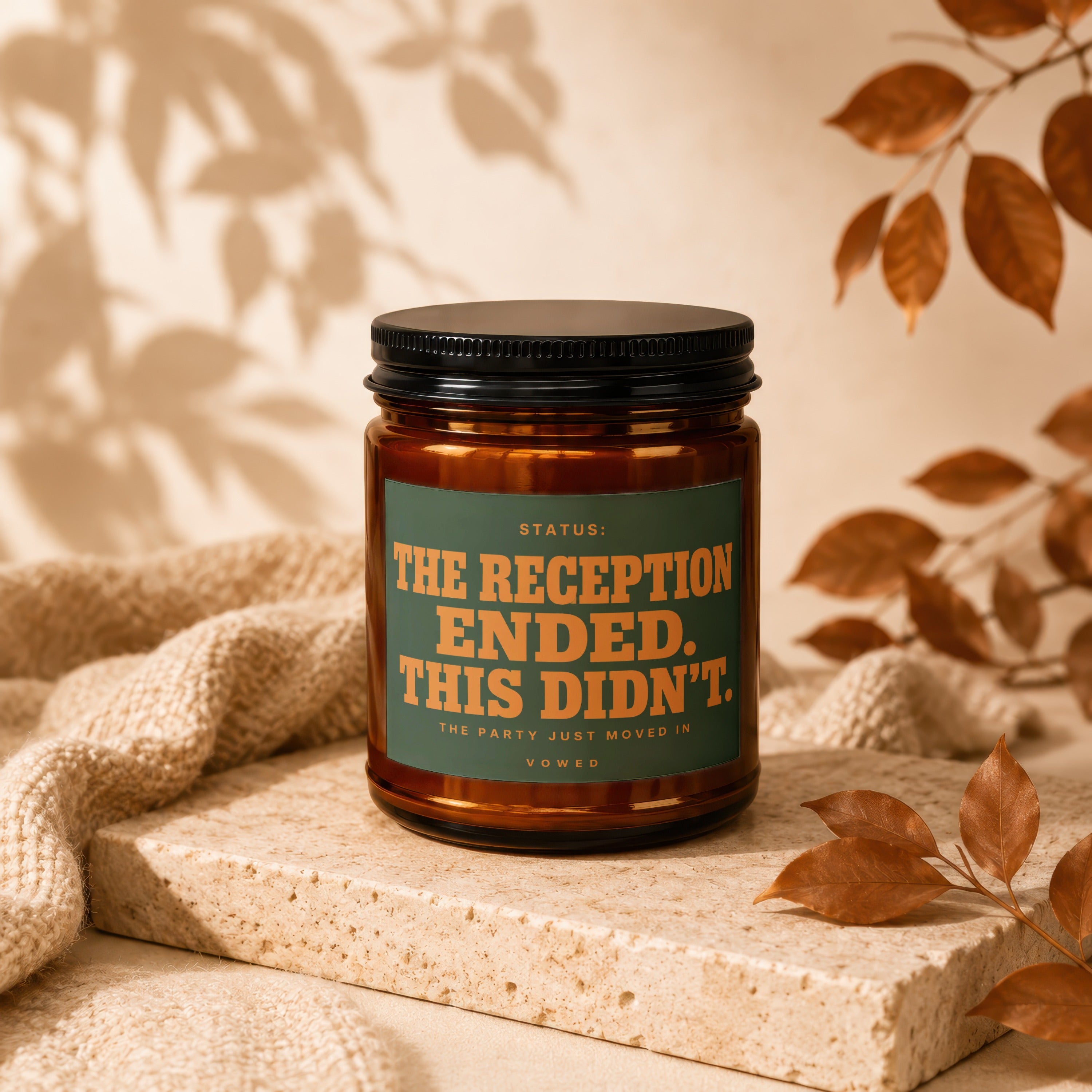 Amber candle with black lid, green label with orange text about a reception.