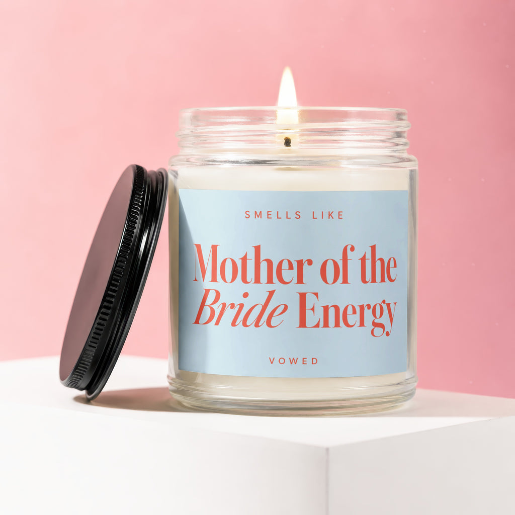 Glass candle with lit wick, reads "Smells Like Mother of the Bride Energy."