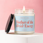 Glass candle with lit wick, reads "Smells Like Mother of the Bride Energy."