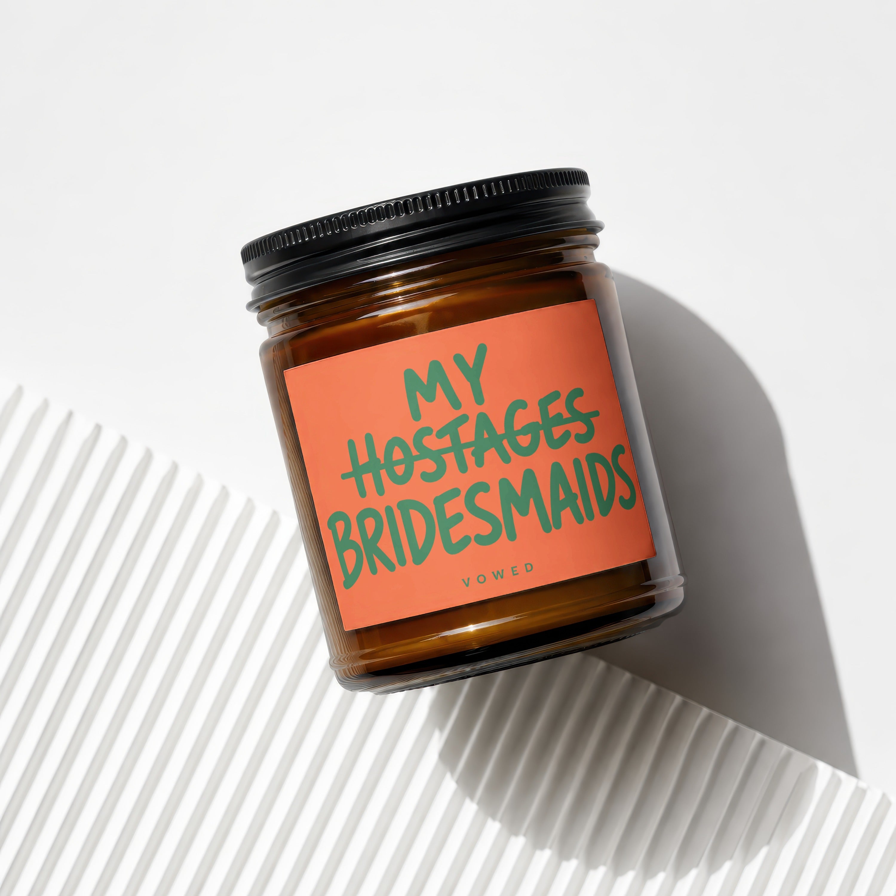 Amber jar candle with "MY HOSTAGES BRIDESMAIDS" text on an orange label.