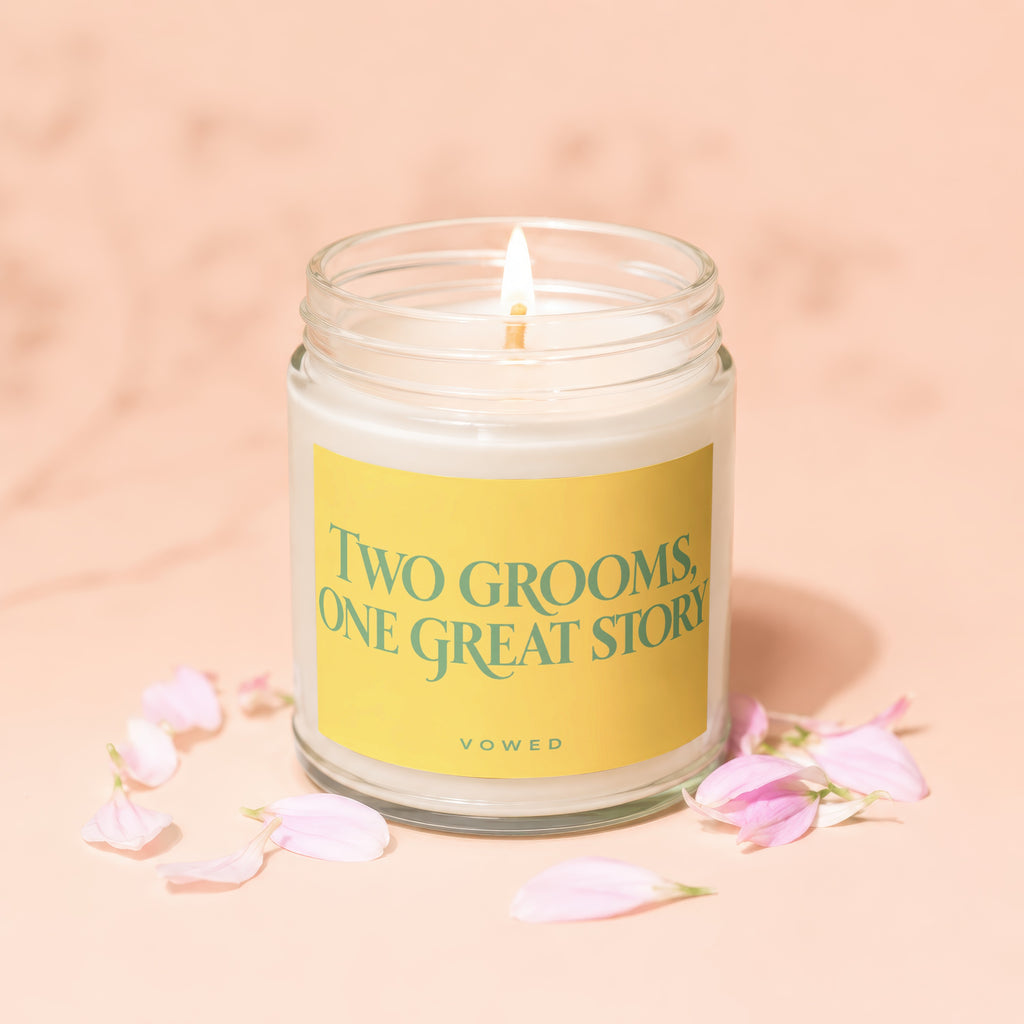 Lit candle with yellow label saying "TWO GROOMS, ONE GREAT STORY" and "VOWED".