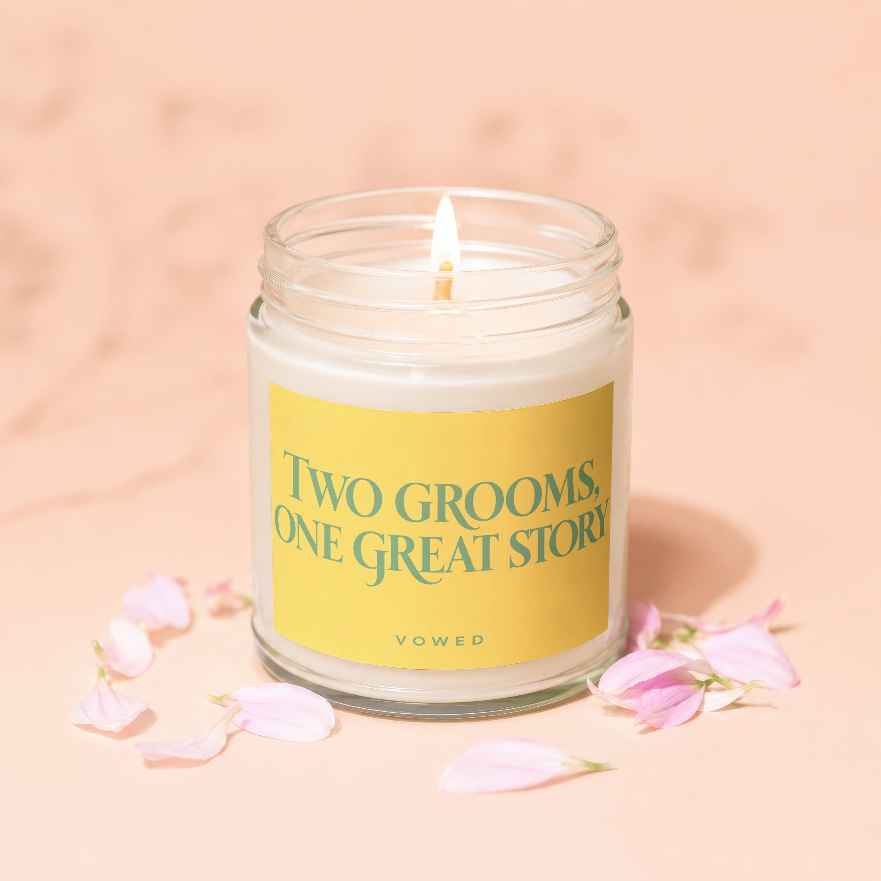 Lit candle with yellow label saying "TWO GROOMS, ONE GREAT STORY" and "VOWED".