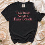 Black t-shirt with "This Bride Needs a Pina Colada" in pink font.