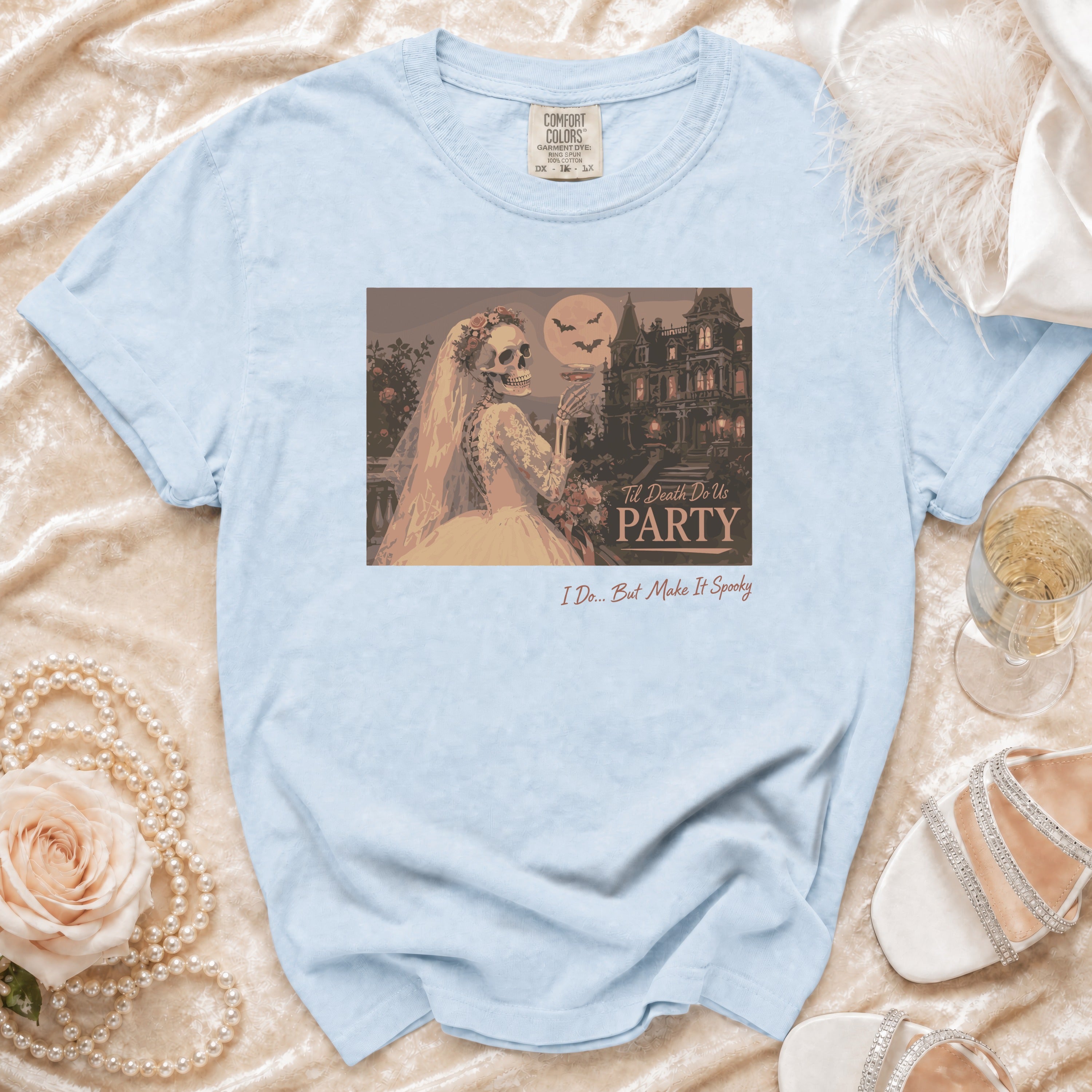 Skeleton bride in a wedding dress holding a drink, with a haunted mansion and bats on the shirt.