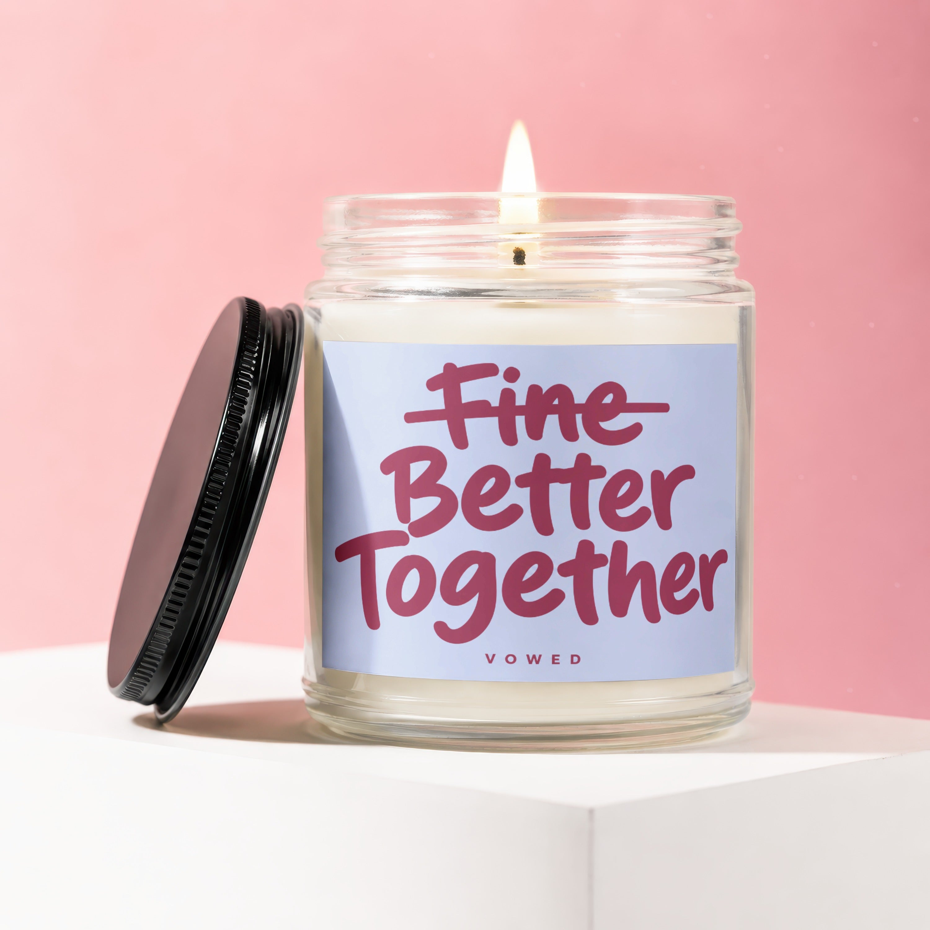 Glass candle with lit flame and lid, reads "Better Together" VOWED.