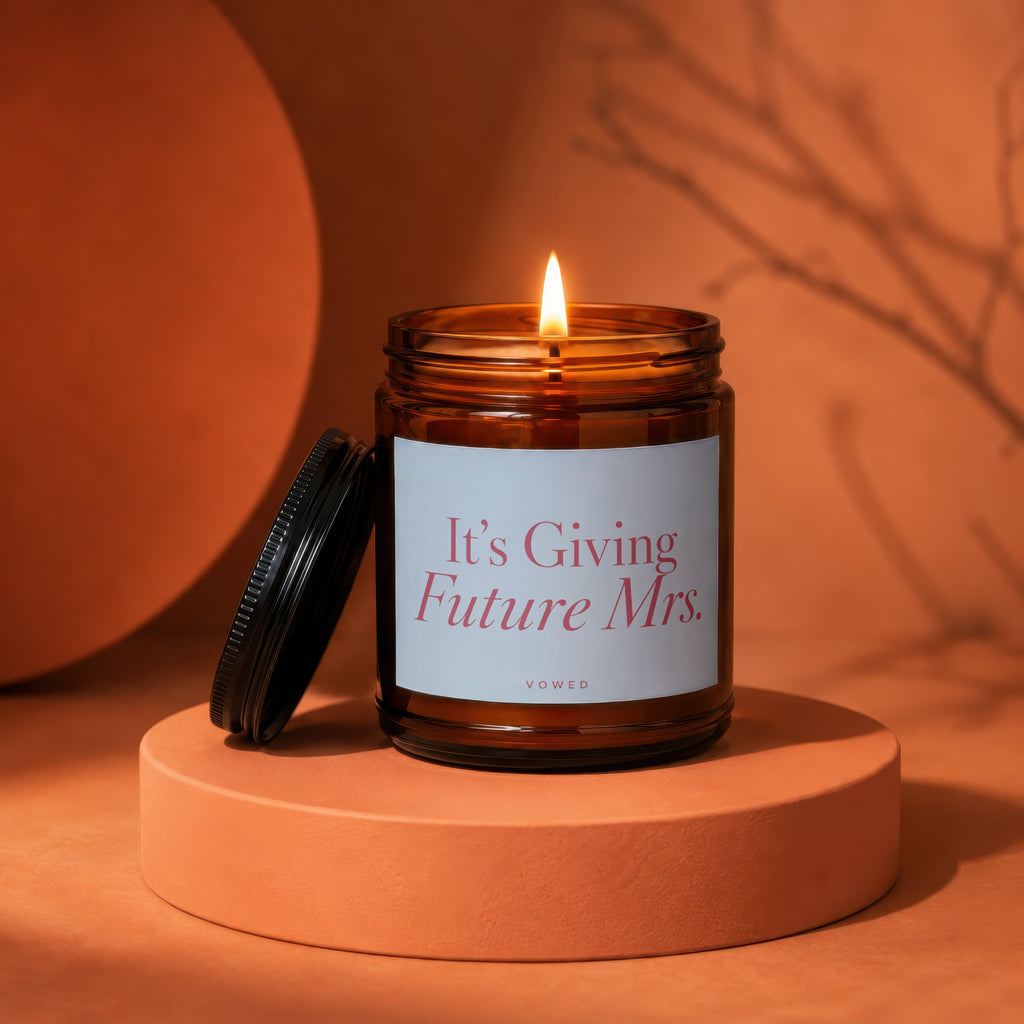 Lit amber glass candle with "It's Giving Future Mrs." text on label.