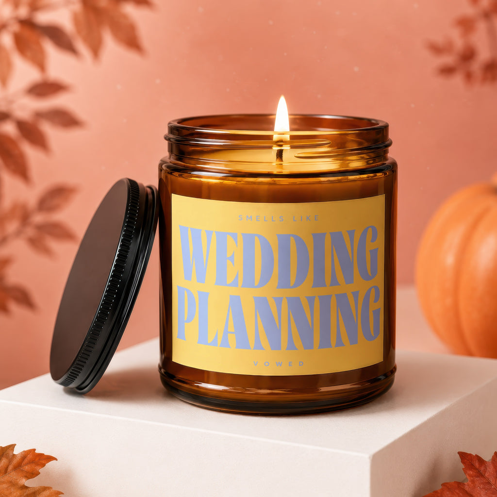 Amber jar candle with lit flame, reads "Smells Like Wedding Planning".