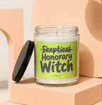 Glass candle with green label reading "Skeptical Honorary Witch Vowed."