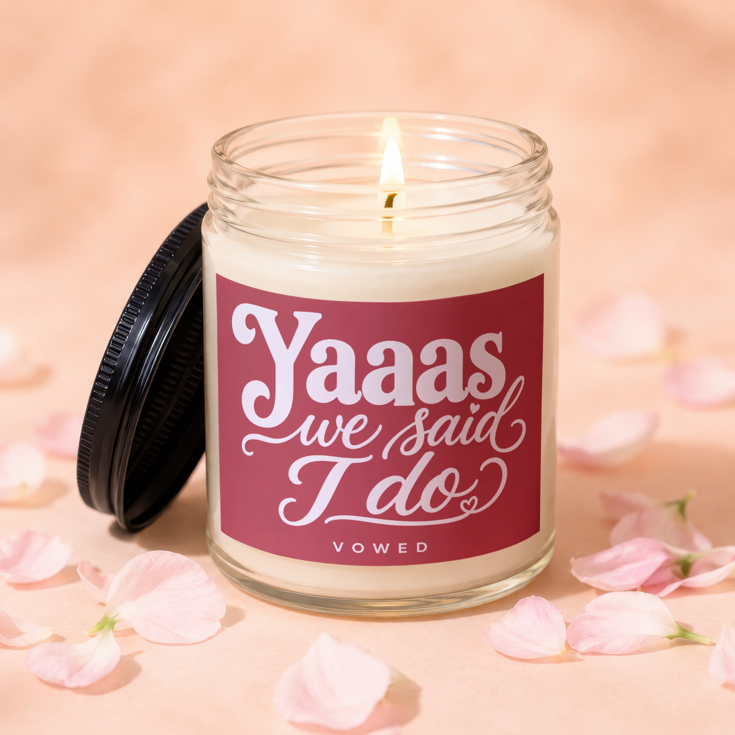 Candle with lit wick and burgundy label reading "Yaaas we said I do"