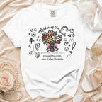 White t-shirt with "Mother of the Bride" text and floral design, saying "I raised her first, now I plan the party."