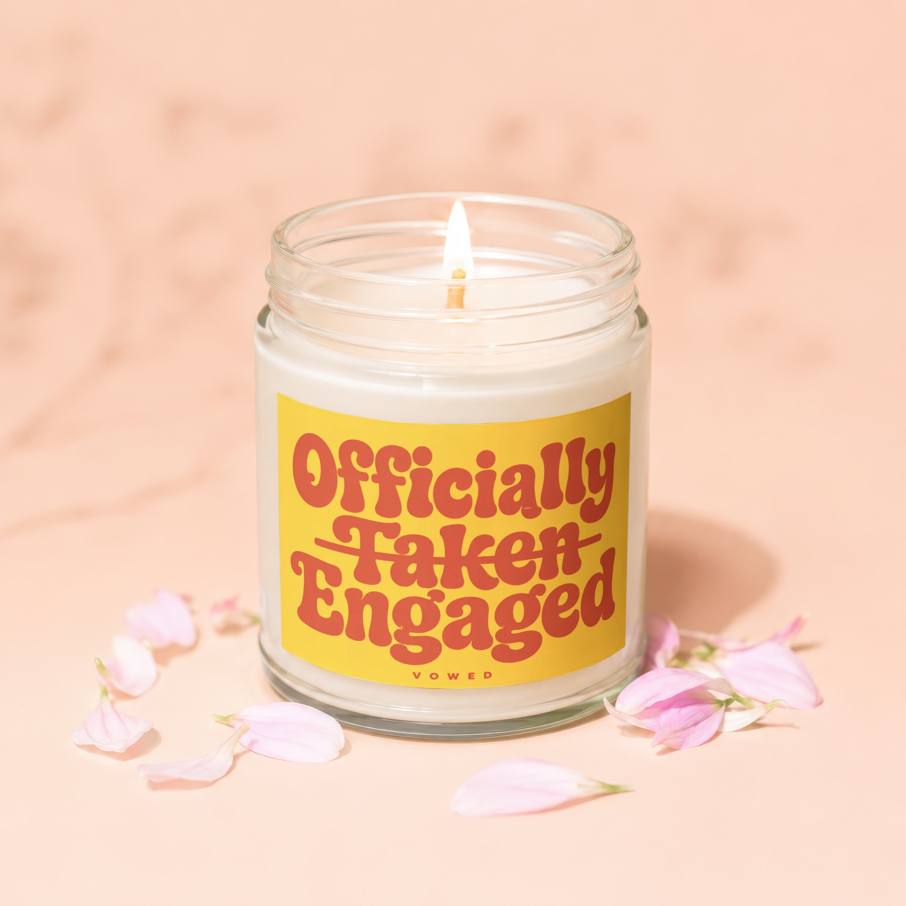 Jar candle with text "Officially Taken Engaged" and surrounding pink petals.