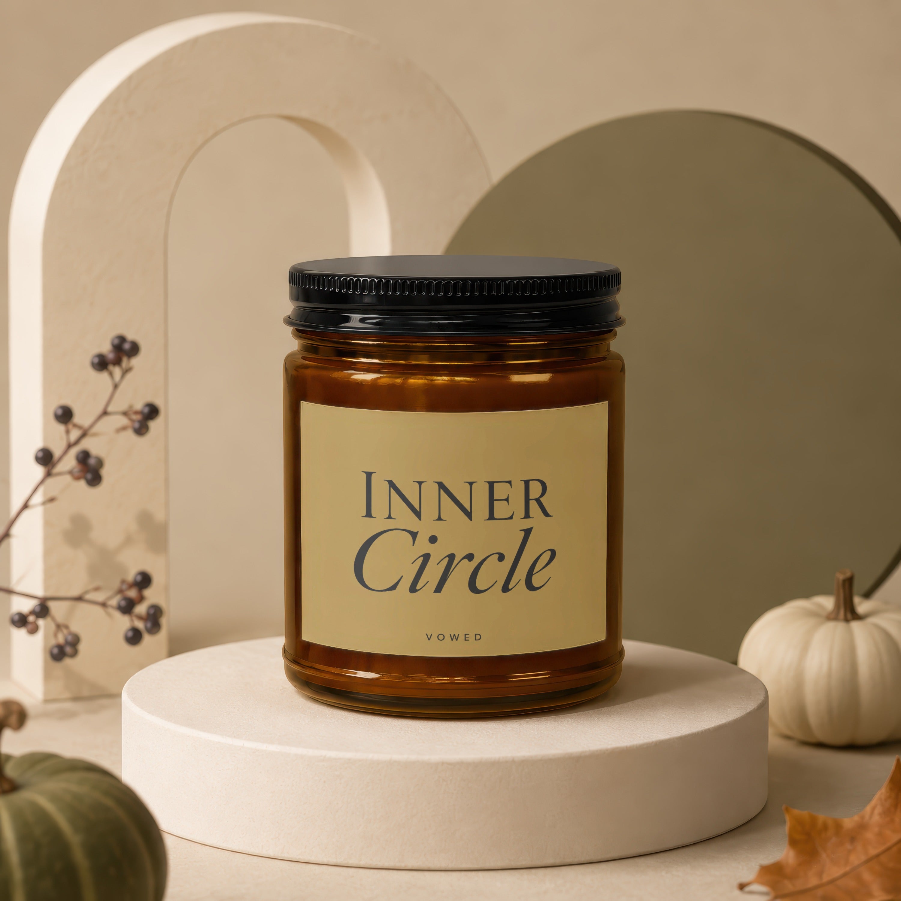 Amber candle with "INNER Circle VOWED" label on cream pedestal.