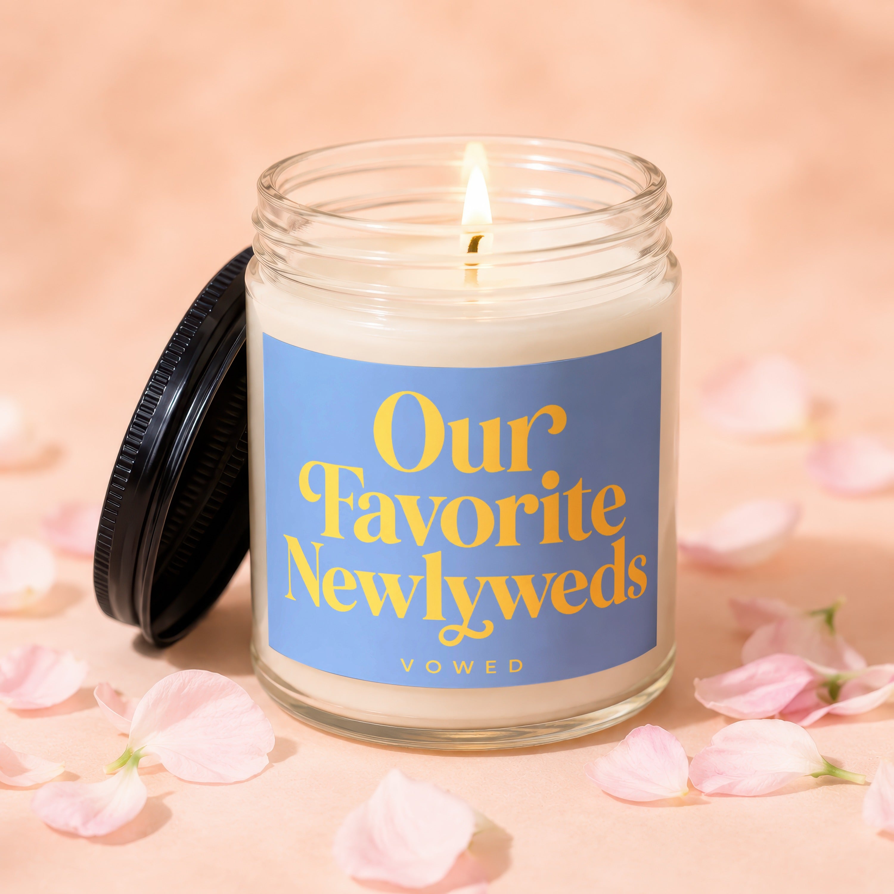 Candle with blue label reading "Our Favorite Newlyweds" surrounded by pink petals.
