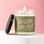 Glass candle with green label reading "Two Grooms, Zero Chill" on pink background.