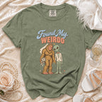 Green t-shirt with Bigfoot in a wedding veil and alien in a suit saying "Found My Weirdo."