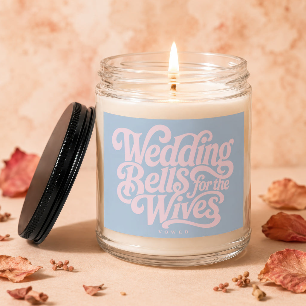 Lit candle with "Wedding Bells for the Wives Vowed" text on a light blue label.