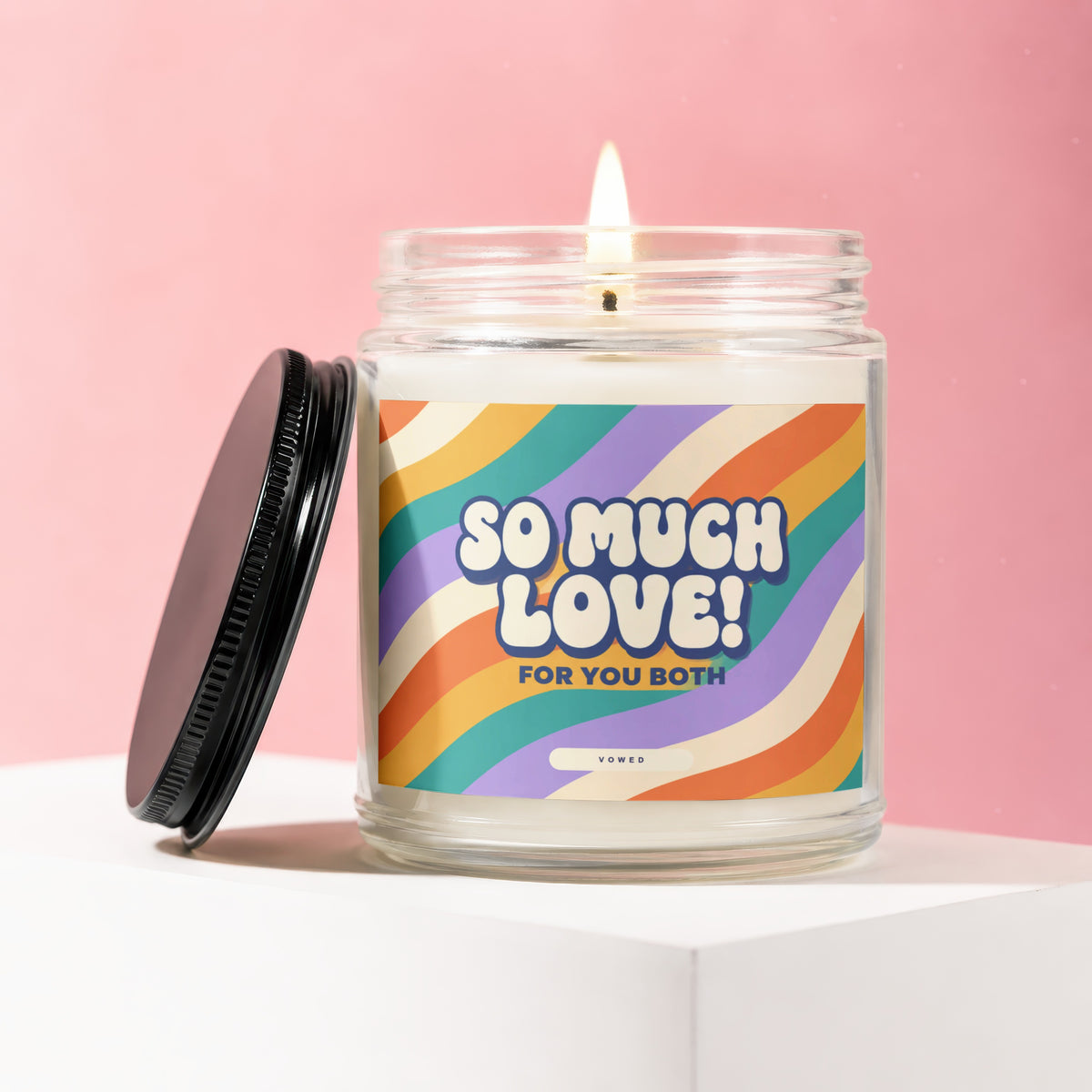Lit candle in a jar with a retro-style label that says "SO MUCH LOVE! FOR YOU BOTH"