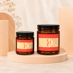Two amber glass candles with black lids and red labels reading "BRIDESMAID."