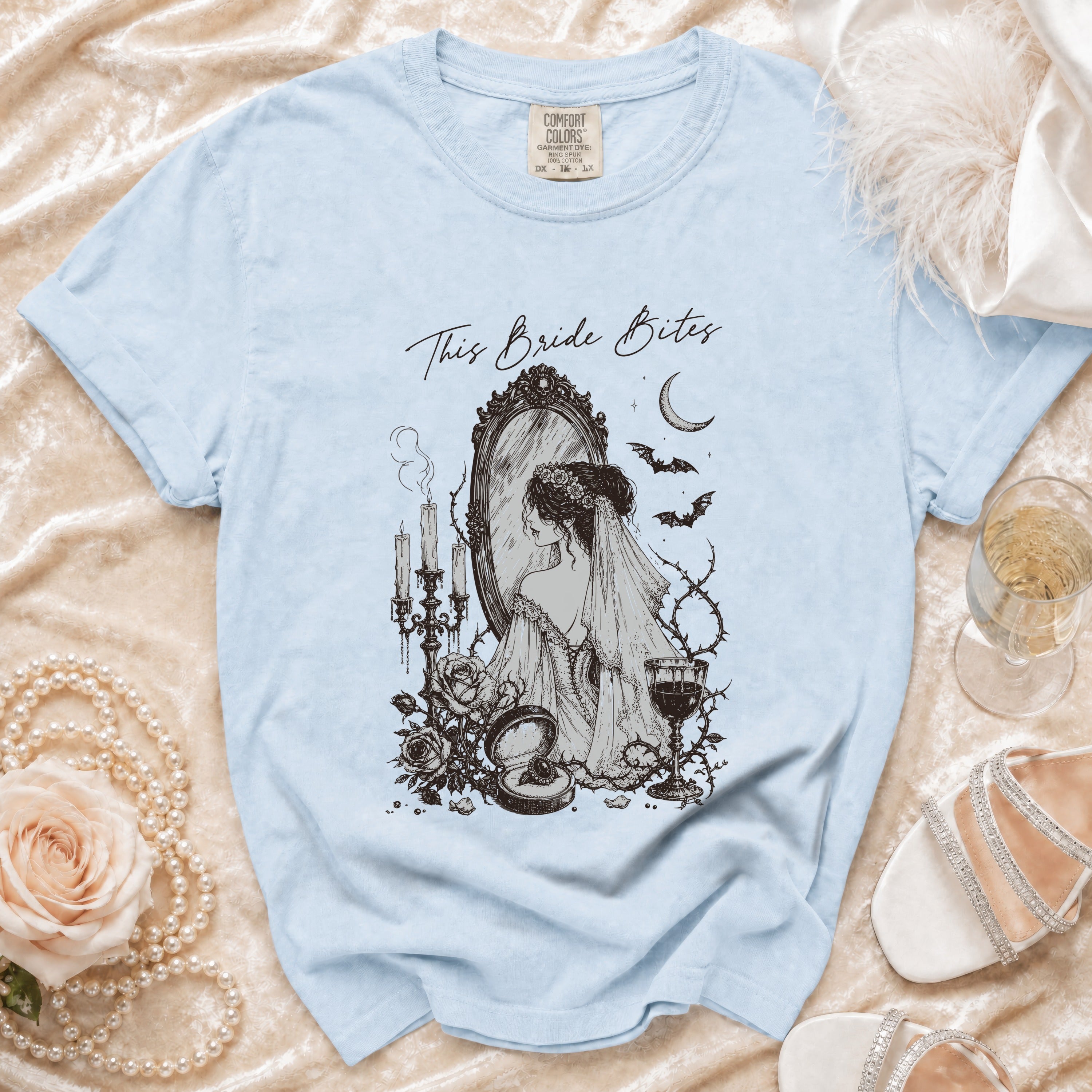 Light blue t-shirt with "This Bride Bites" graphic of bride at mirror with gothic elements.