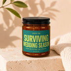 Glass jar with black lid featuring a teal label that reads "Surviving Wedding Season Seven Invitations. One Survivor. Vowed."