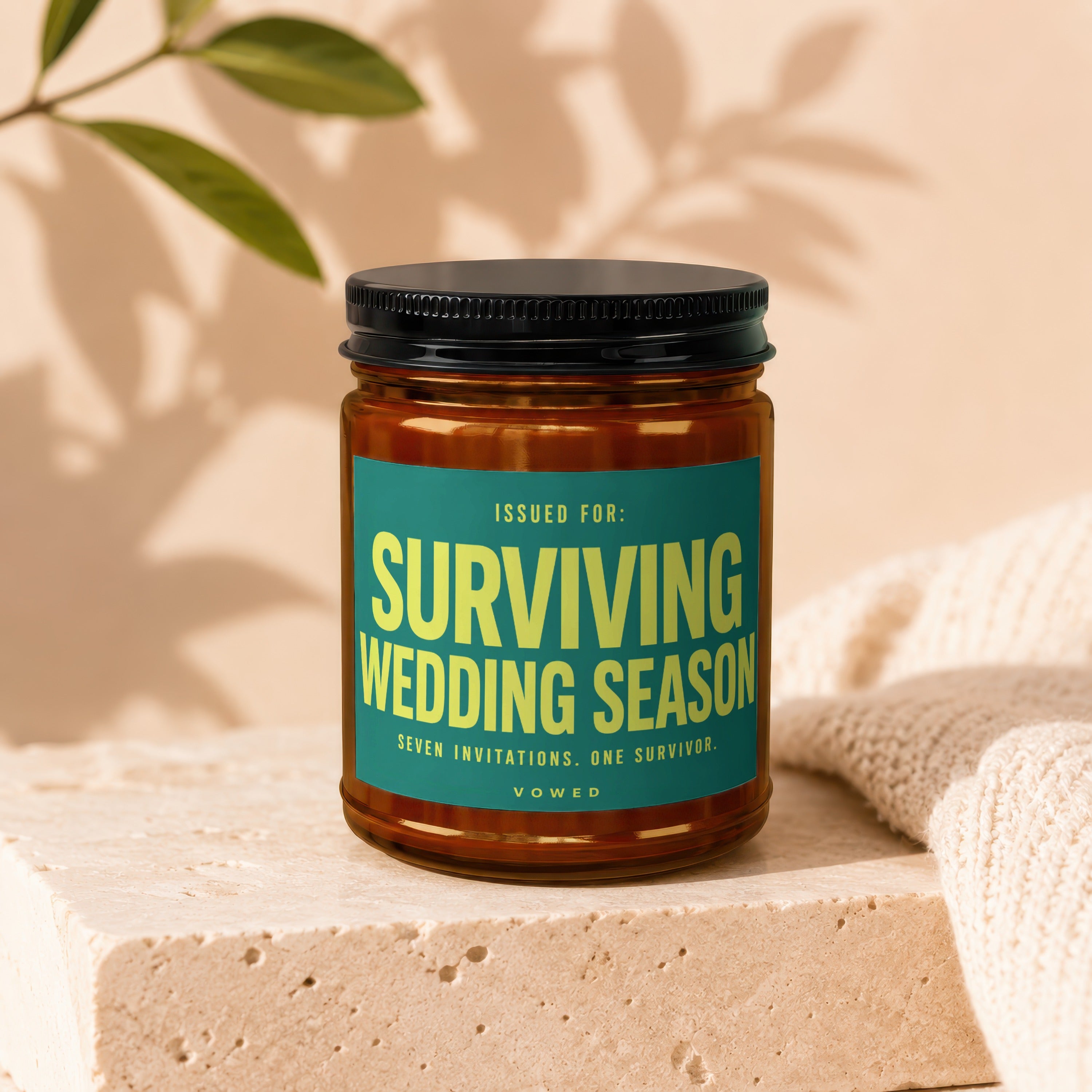 Glass jar with black lid featuring a teal label that reads "Surviving Wedding Season Seven Invitations. One Survivor. Vowed."