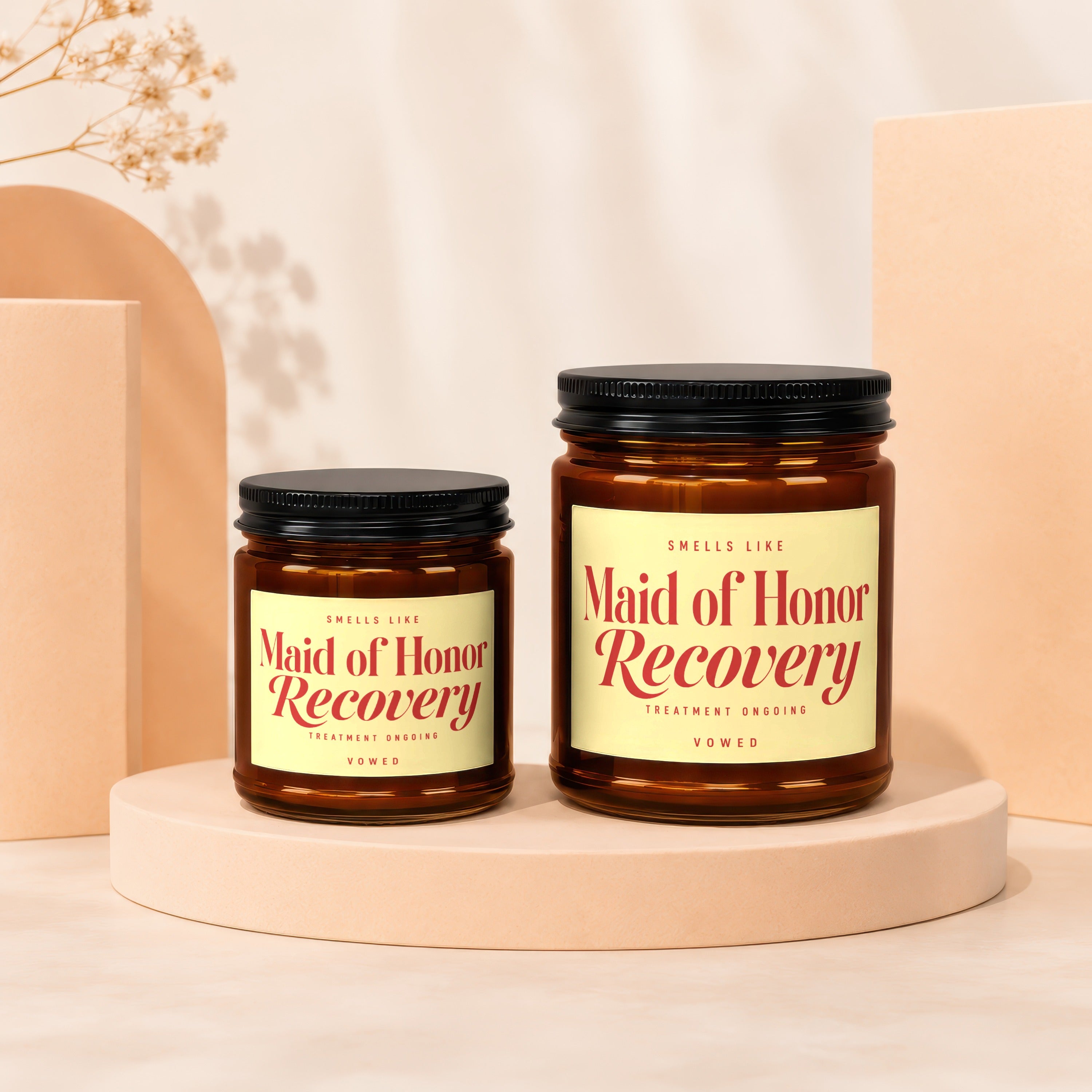 Two amber glass candles with black lids labeled "Maid of Honor Recovery."