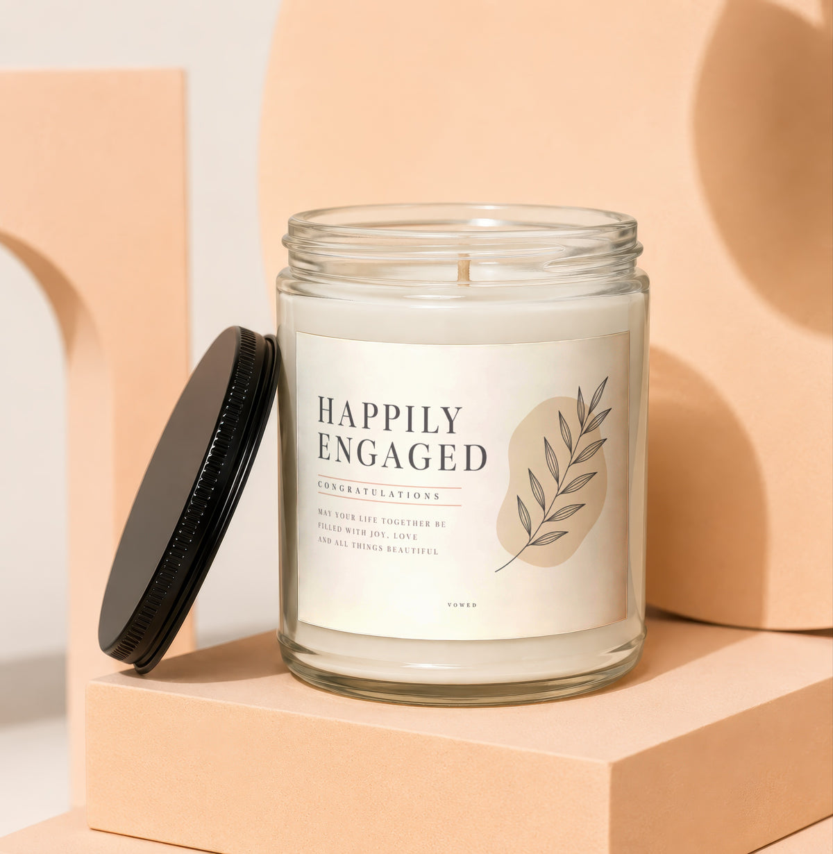Candle with "Happily Engaged" label, floral design, and congratulatory message.