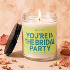 Lit candle in glass jar with "You're in the Bridal Party" text.