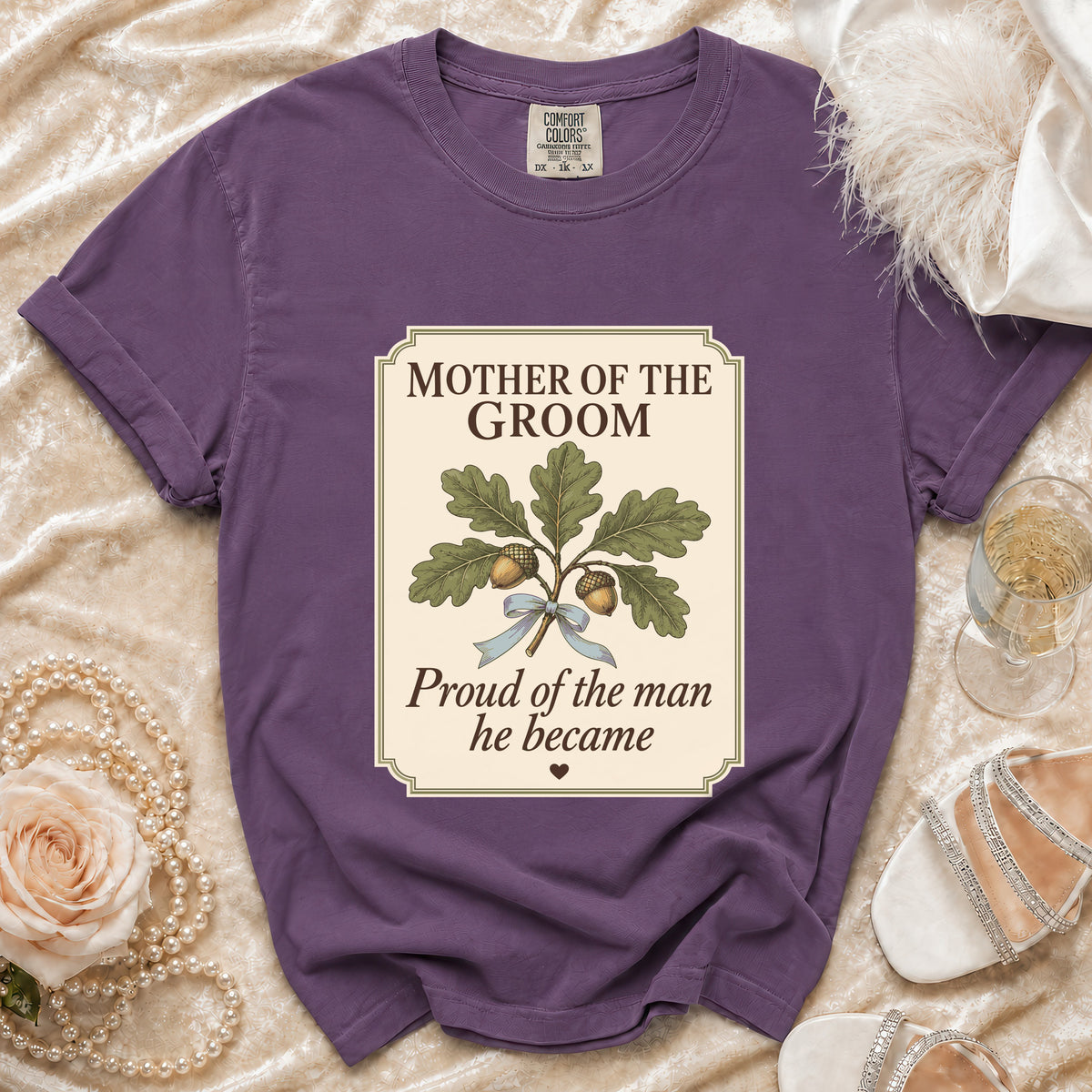 Purple t-shirt with "Mother of the Groom, Proud of the man he became" text and oak illustration.