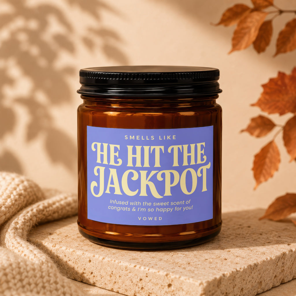 Amber jar candle with a purple label saying "He Hit The Jackpot."