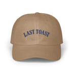 Tan baseball cap with "LAST TOAST" embroidered in blue on the front.