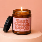 Lit amber glass candle with a pink label that reads "Best Person Energy".