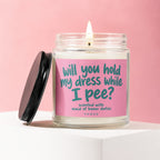 Candle with pink label reading "Will you hold my dress while I pee?"