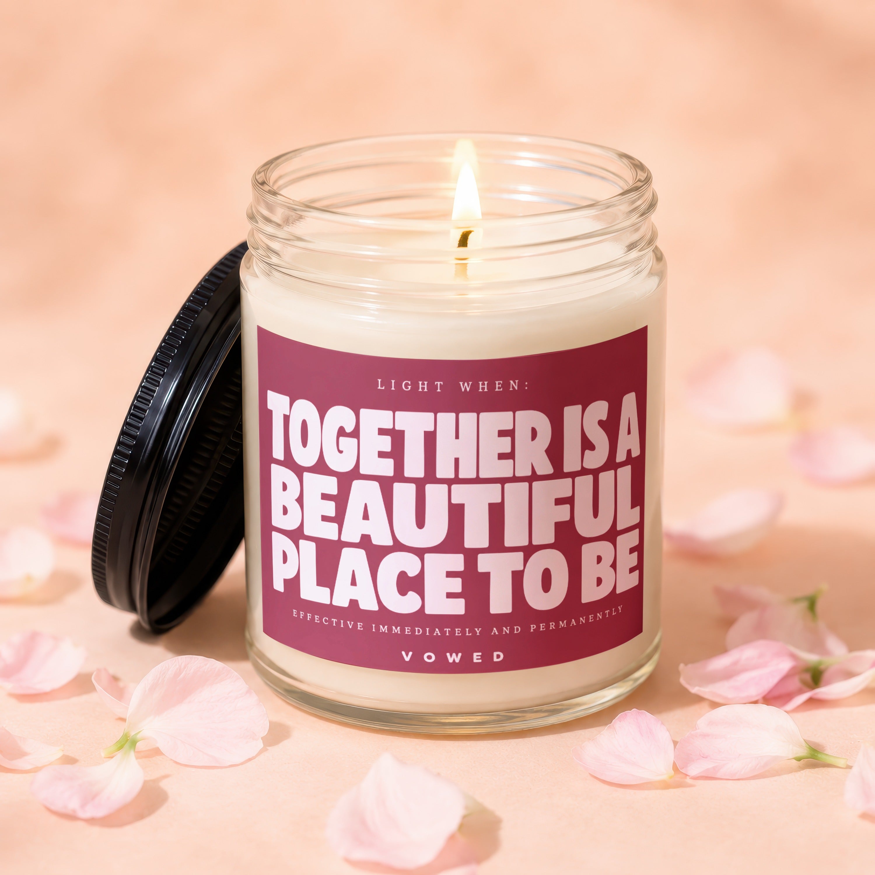 Glass candle with lit wick and pink petals, says "Together is a beautiful place to be".