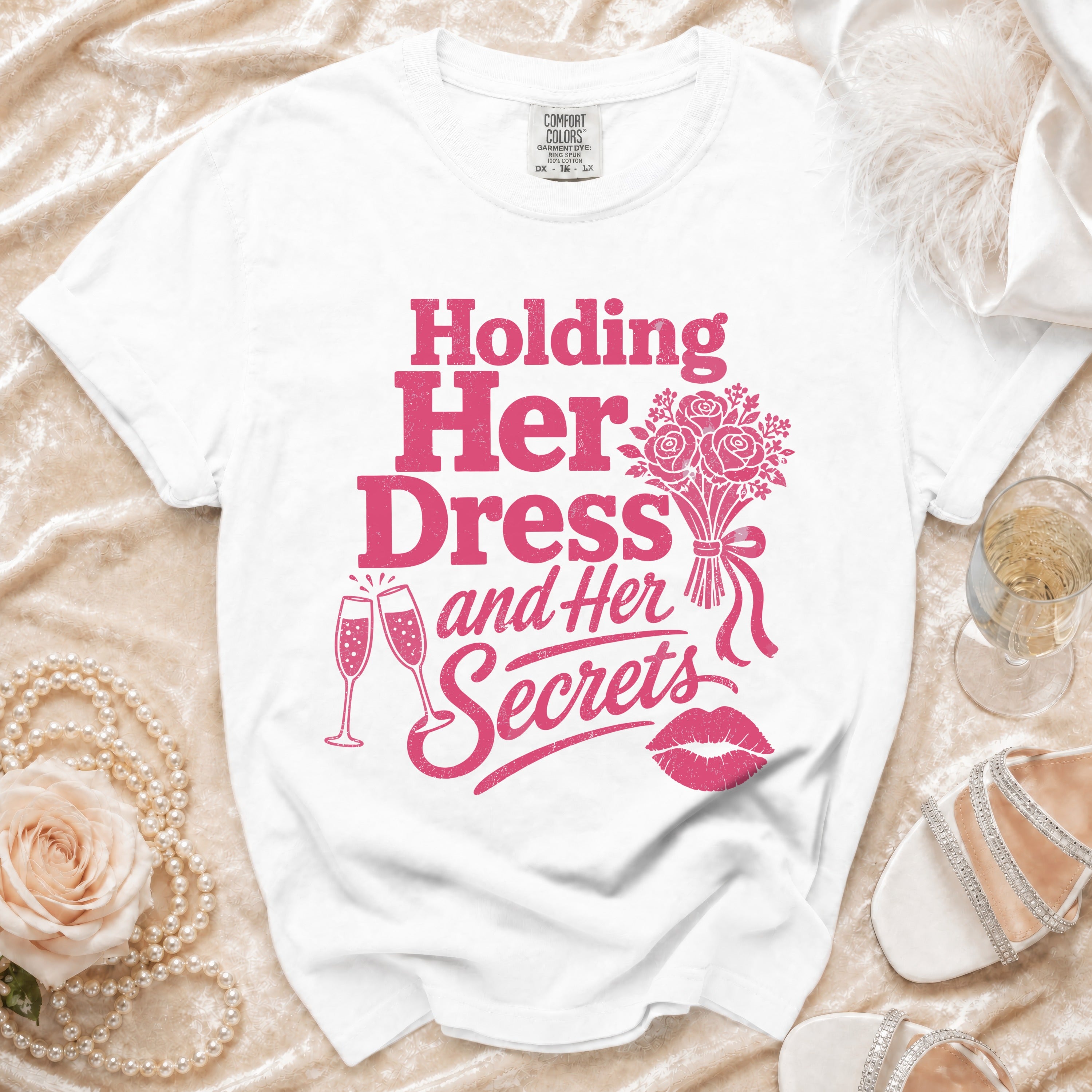 White t-shirt with pink graphic text "Holding Her Dress and Her Secrets".