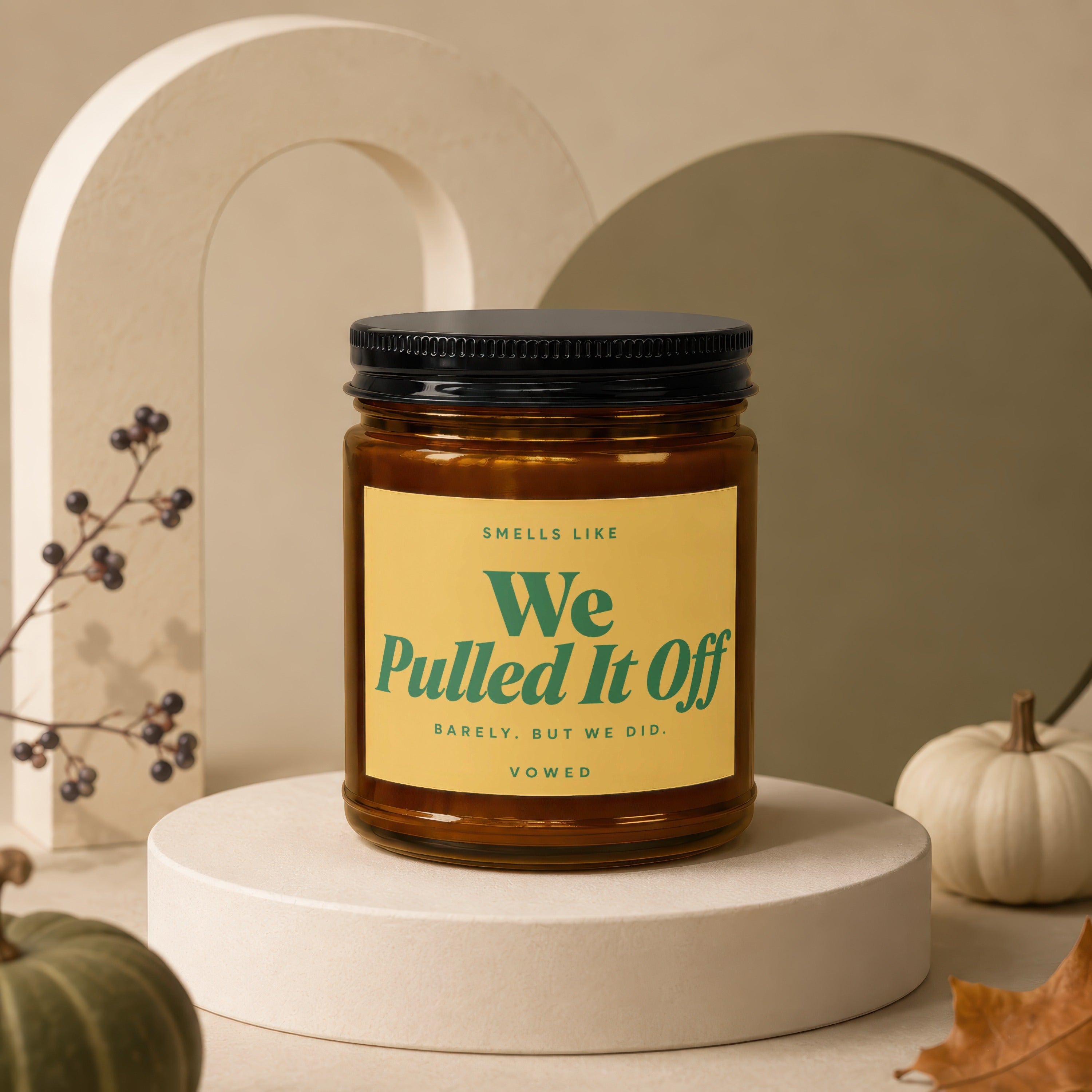 Candle with black lid and yellow label reading "Smells Like We Pulled It Off BARELY. BUT WE DID. VOWED".