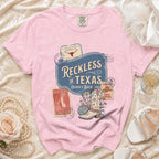 Pink t-shirt with "Reckless in Texas" and disco cowboy boot graphic.