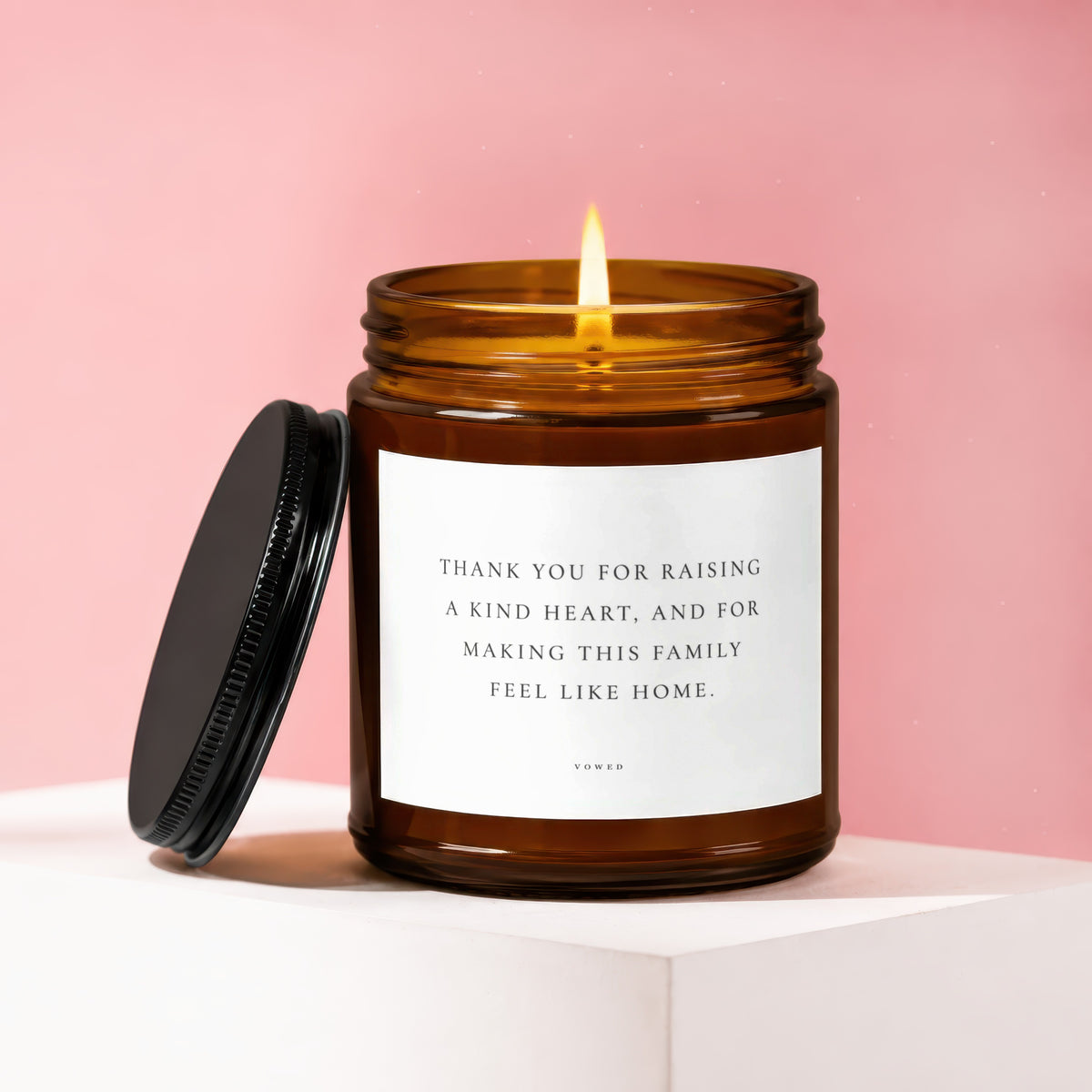 Amber glass candle with lit flame, text "Thank you for raising a kind heart..."
