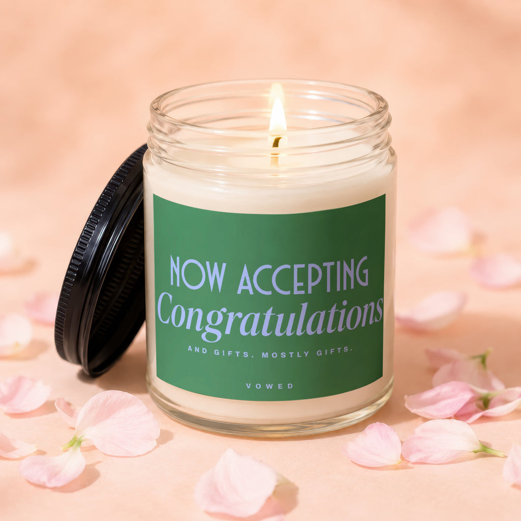 Jar candle with green label reading "NOW ACCEPTING Congratulations And gifts. Mostly gifts. VOWED."