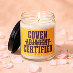 Jar candle with orange label reading "Coven Adjacent Certified".
